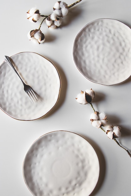 Belles assiettes sur fond blanc avec du coton. Belle mise en page