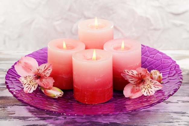 Belles bougies avec des fleurs sur table sur fond gris