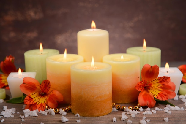 Belles bougies avec des fleurs sur table sur fond marron