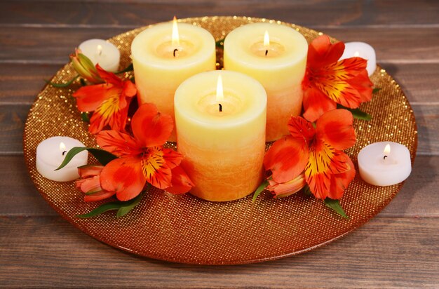 Belles bougies avec des fleurs sur table sur fond marron