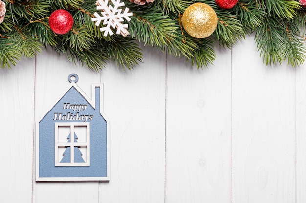 Belles branches d'un arbre de Noël avec des cônes et des jouets sur un fond en bois blanc avec l'inscription Joyeux Noël
