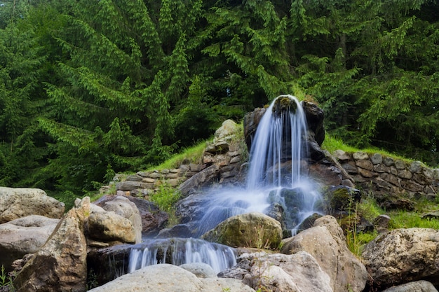 De belles cascades artificielles, à l’arrière-plan sont des pins verts.