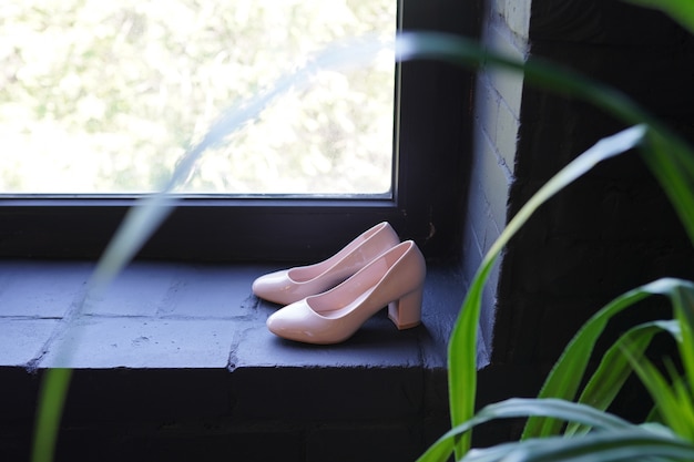 Belles Chaussures De Mariée Stiletto Doré. Chaussures De Mariage De Designer De Luxe Sur Fenêtre Sombre.