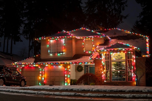 Belles décorations de Noël à l'extérieur de la maison la nuit. Maison décorée de lumières jaunes