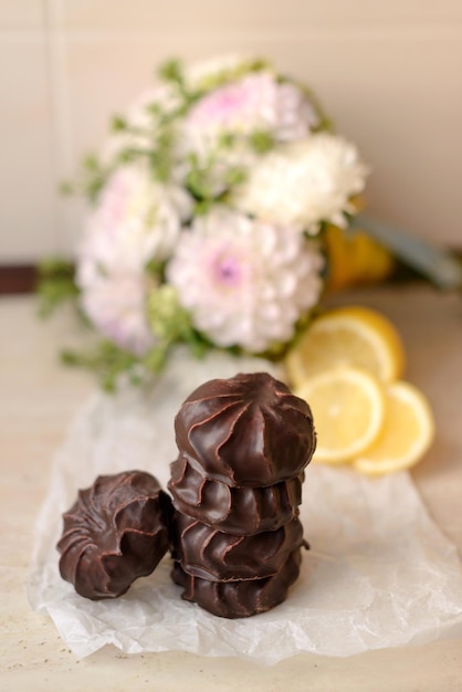 Belles délicieuses guimauves au chocolat sur un tableau blanc avec du citron et du thé