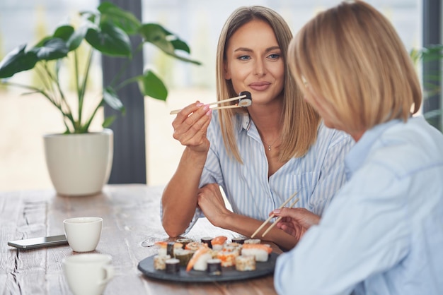 Belles deux filles adultes dans la maison en train de manger des sushis