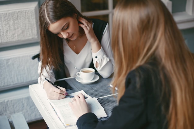 belles et élégantes jeunes femmes d&#39;affaires assis dans un café et de travail