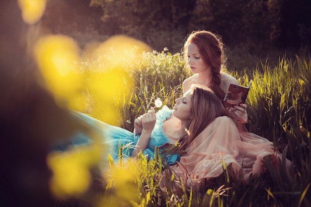 Belles femmes appréciant le jardin lilas, jeunes femmes avec des fleurs dans un parc verdoyant. adolescents joyeux marchant en plein air. couleur de style lumière douce