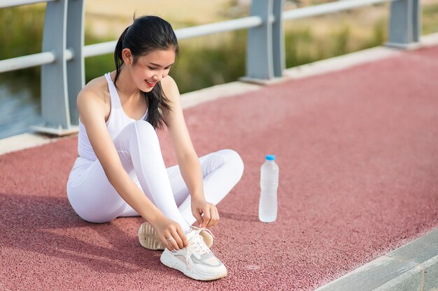 Belles femmes asiatiques dans le corps d'échauffement de vêtements de sport pour préparer l'exercice en plein air. Concept de femmes en bonne santé. Entraînement en cours d'exécution.