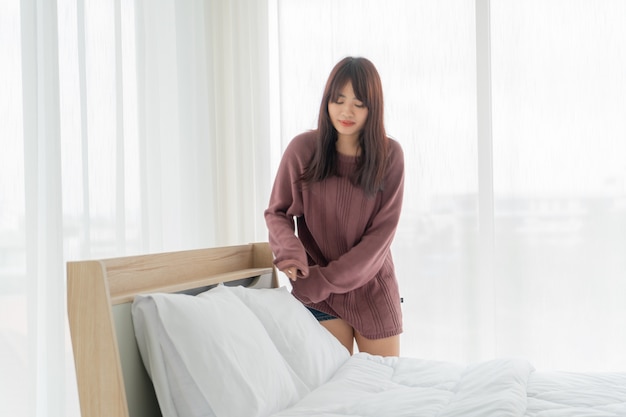 Belles femmes asiatiques faisant le lit dans la chambre avec un drap propre blanc