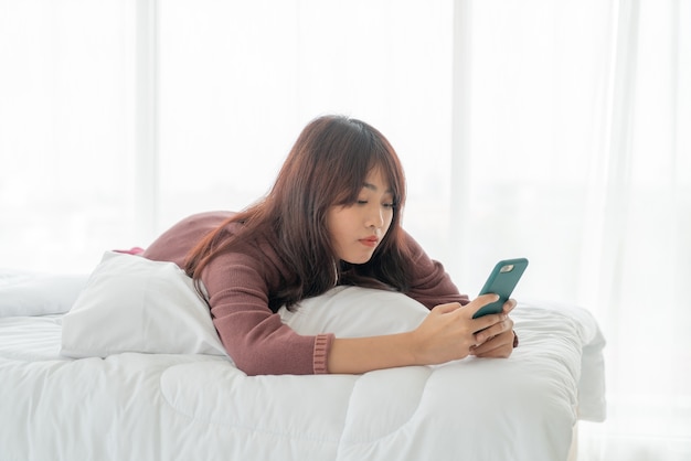 belles femmes asiatiques jouant smartphone sur lit