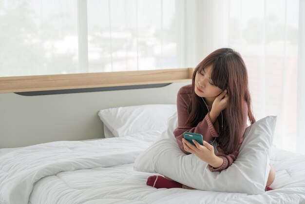 belles femmes asiatiques jouant smartphone sur lit