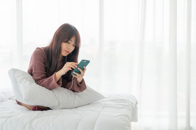 belles femmes asiatiques jouant smartphone sur lit