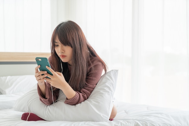 belles femmes asiatiques jouant smartphone sur lit