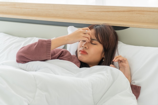 belles femmes asiatiques maux de tête et dormir sur le lit