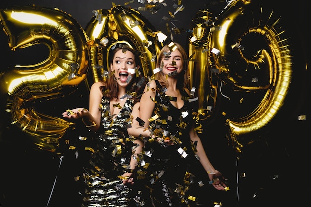Belles femmes célébrant le nouvel an. Heureuses filles magnifiques dans des robes de soirée sexy élégantes tenant des ballons d'or 2019, s'amusant à la fête du nouvel an. Célébration de vacances. Image de haute qualité
