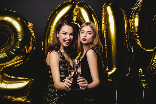 Belles femmes célébrant le nouvel an. Heureuses filles magnifiques dans des robes de soirée sexy élégantes tenant des ballons d'or 2019, s'amusant à la fête du nouvel an. Célébration de vacances. Image de haute qualité