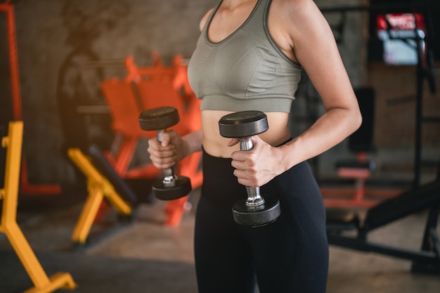 Belles femmes exercice de formation avec haltères dans la salle de gym, concept de remise en forme sport