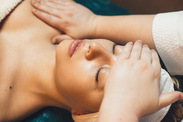 Belles femmes leanin avec les yeux fermés doina routine de soins de la peau dans un spa de bien-être