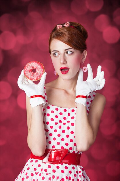 Belles femmes rousses avec beignet. Photo dans un style rétro avec bokeh en arrière-plan.