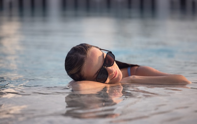 Belles femmes se détendre au bord de la piscine de luxe. Fille à la piscine de la station thermale de voyage. Vacances de luxe d'été.