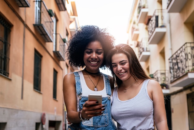 Belles femmes utilisant un mobile dans la rue. Concept de la jeunesse.