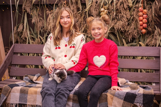 belles filles avec un chat dehors en automne près de la maison