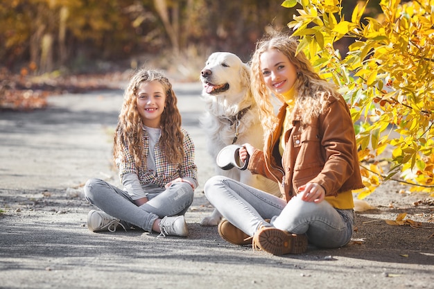 Belles filles avec golden retriever. Deux sœurs en plein air s'amusant propriétaires en automne.