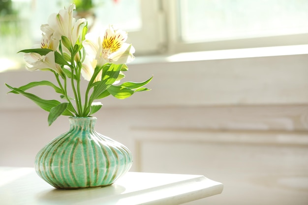 Belles fleurs d'Alstroemeria dans des vases aigue-marine sur fond de fenêtre