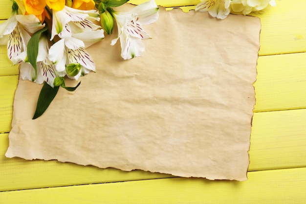 Belles fleurs d'Alstroemeria et feuille vide sur table en bois