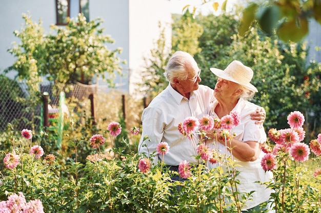 Avec de belles fleurs Beau couple de personnes âgées est dans le jardin ensemble