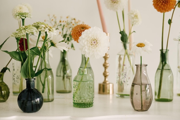 De belles fleurs dans des vases en verre décorent la cheminée à la maison