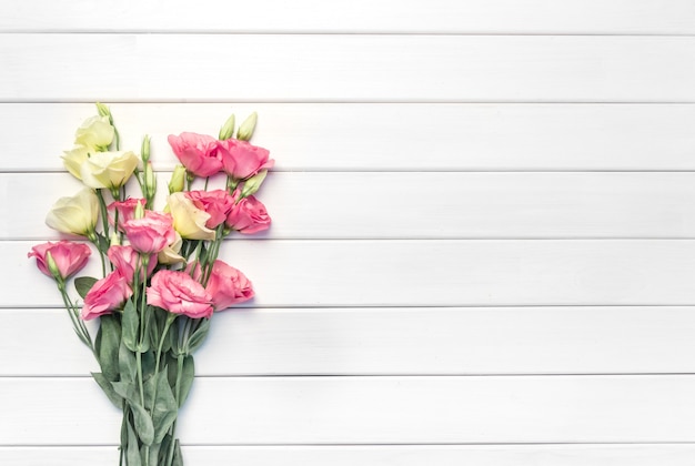 Belles fleurs d'eustoma rose sur table en bois blanc, vue du dessus