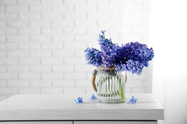 Belles fleurs de jacinthe dans un vase en verre sur fond de mur de briques