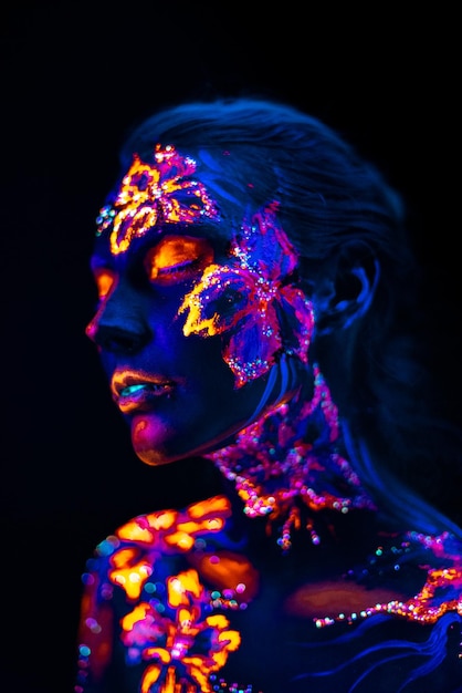 Belles fleurs à la lumière UV sur le visage et le corps d&#39;une jeune fille