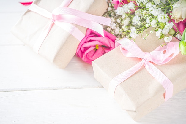 Belles Fleurs De Printemps Sur Fond En Bois Blanc. Composition Florale Festive Avec Des Coffrets Cadeaux En Papier Kraft. Saint Valentin, Fête De La Femme, Carte De Voeux Fête Des Mères. Vue De Dessus à Plat