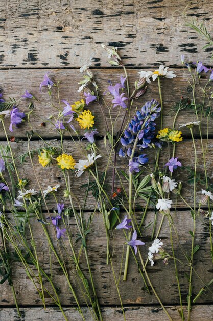 Photo belles fleurs sauvages d'été à plat sur fond de bois rustique rassemblement et arrangement de fleurs à la maison dans la campagne composition de bouquet de fleurs sauvages colorées