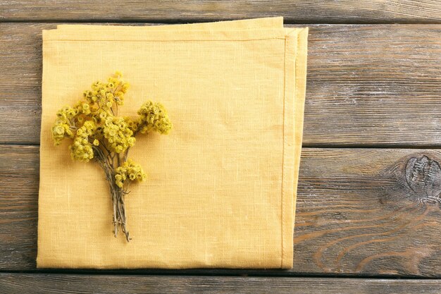 Photo belles fleurs sèches sur une serviette sur fond de bois