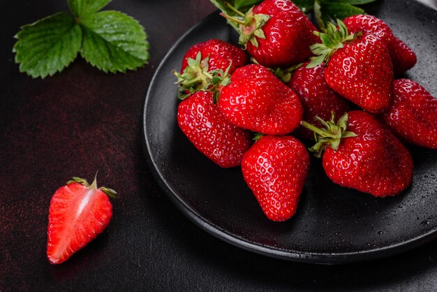 Belles fraises fraîches juteuses sur la surface en béton de la table