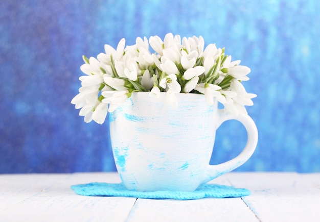 De belles gouttelettes de neige dans un vase sur une table en bois sur un fond lumineux
