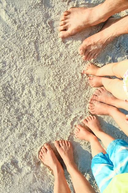 Belles jambes de famille sur le sable au bord de la mer