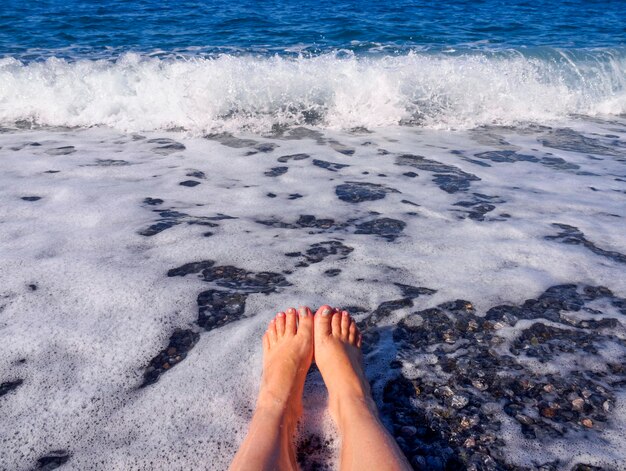 Belles jambes femelles dans la mousse de l'eau de mer en mer Égée un jour ensoleillé en Grèce