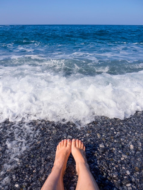 Belles jambes femelles dans la mousse de l'eau de mer en mer Égée un jour ensoleillé en Grèce