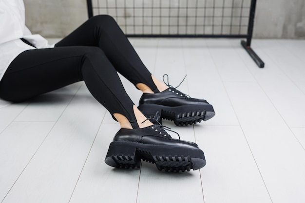 Belles jambes féminines en bottes noires en cuir sur fond blanc Espace de copie