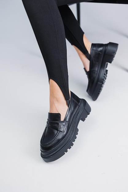 Belles jambes féminines en mocassins en cuir noir et leggings noirs Chaussures pour femmes d'été