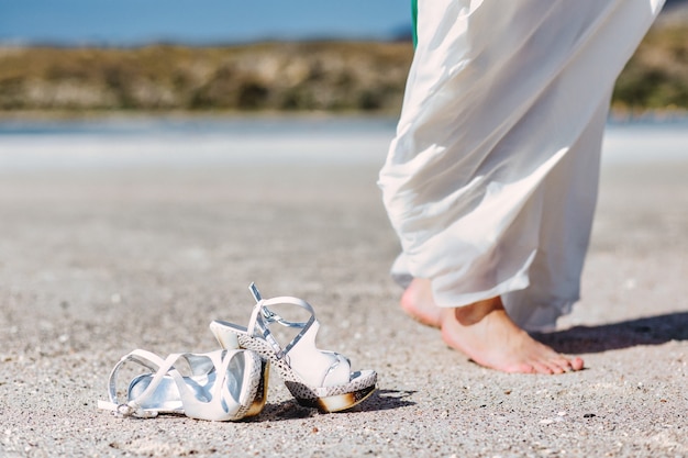 Belles jambes de femme sur les pieds de plage marchant sur le sable