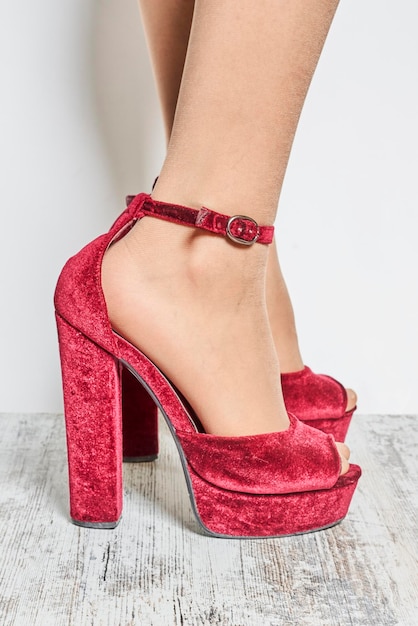 Belles jambes femme portant des chaussures rouges debout contre un mur blanc