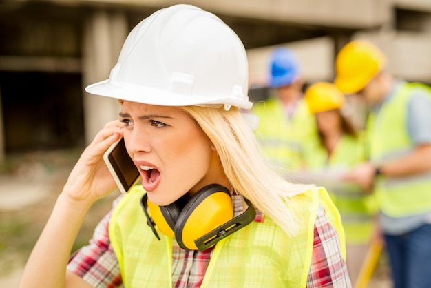 Belles jeunes femmes architectes de construction utilisant le téléphone sur un chantier de construction.