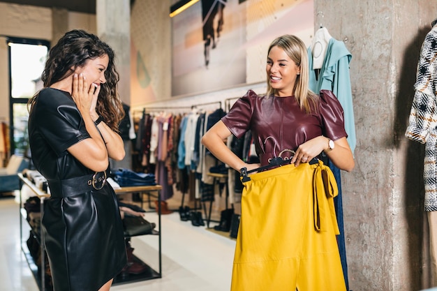 Belles jeunes femmes essayant des vêtements élégants dans une boutique ou un magasin coûteux.