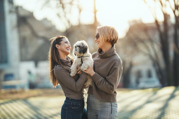 De belles jeunes femmes de la mode passent du temps avec leur adorable chien de compagnie à jouer, jouant dans la rue de la ville.